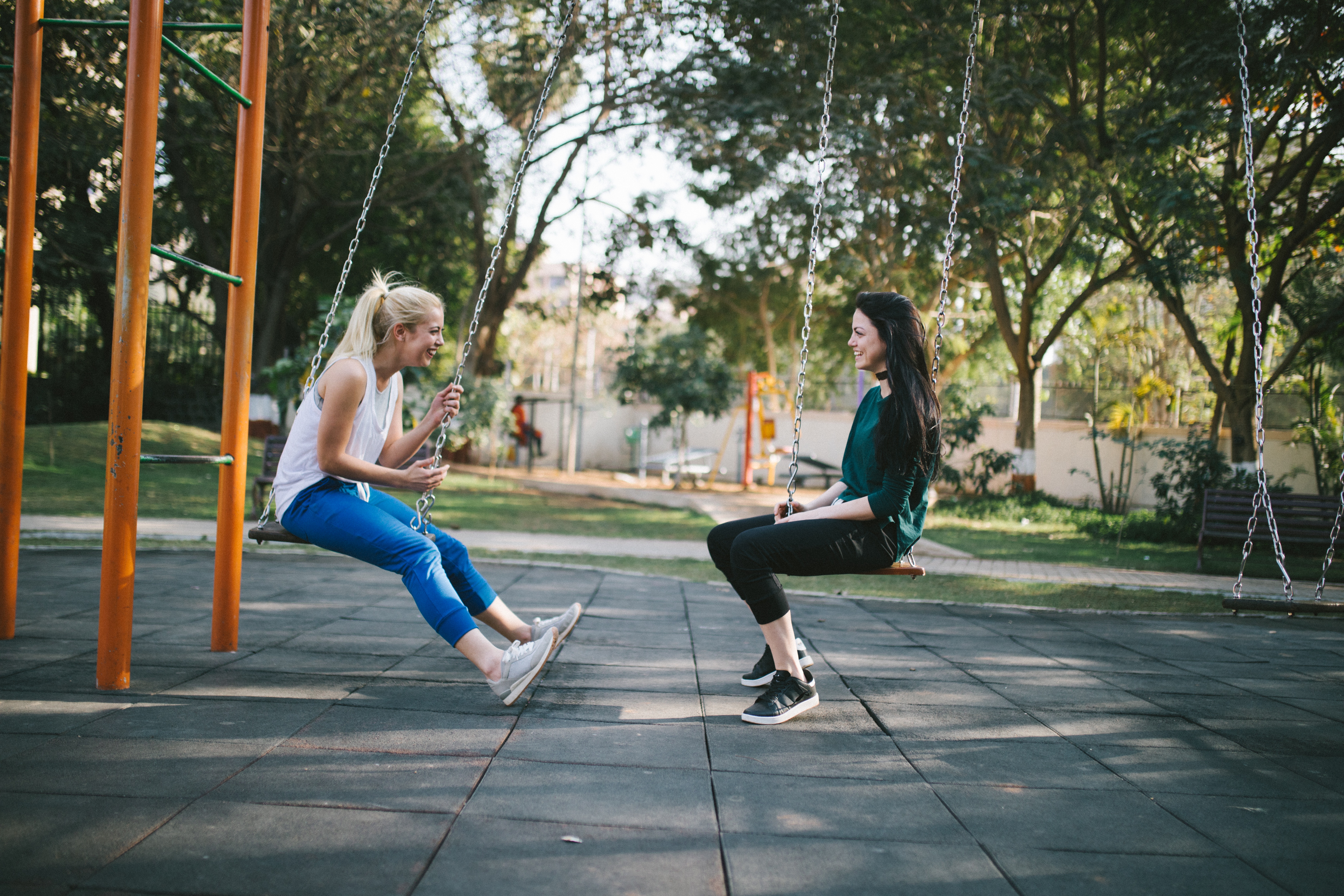 Two women on swings having a conversation while tackling social anxiety.