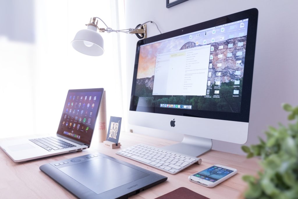 A laptop, desktop and mobile phone on a table