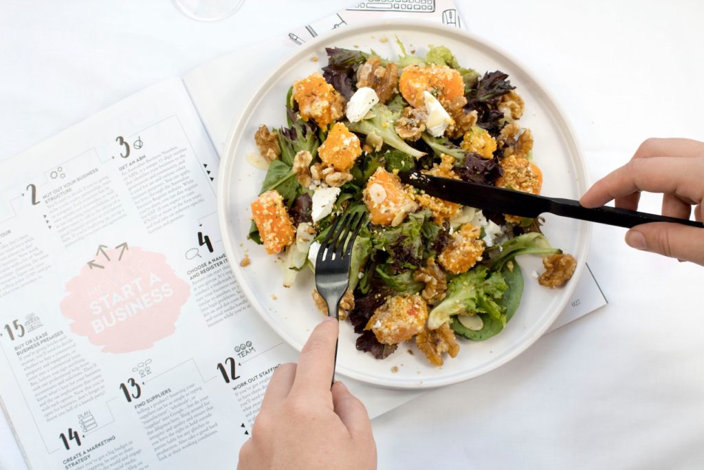 A person having salad while reading magazine
