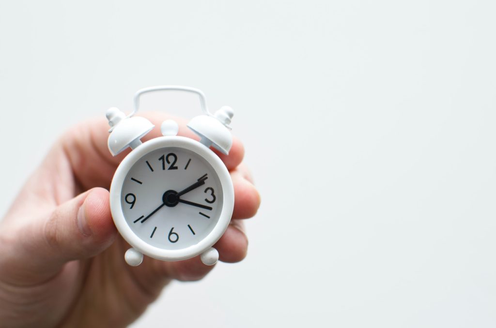 A hand holding a tiny clock