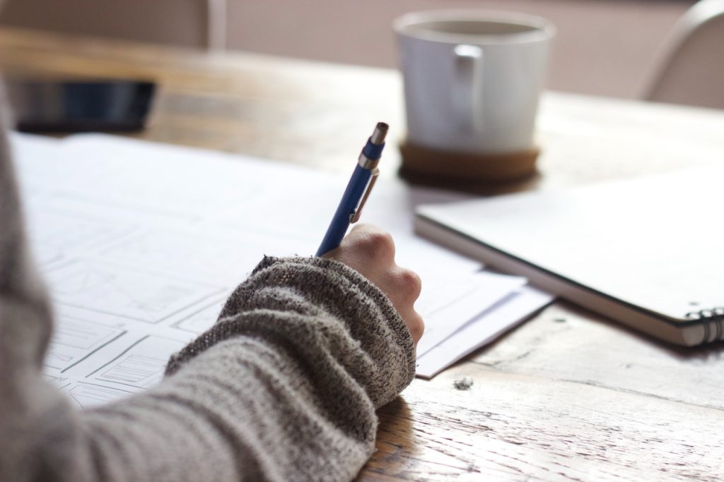 A woman working on a sheet with coffee on the table