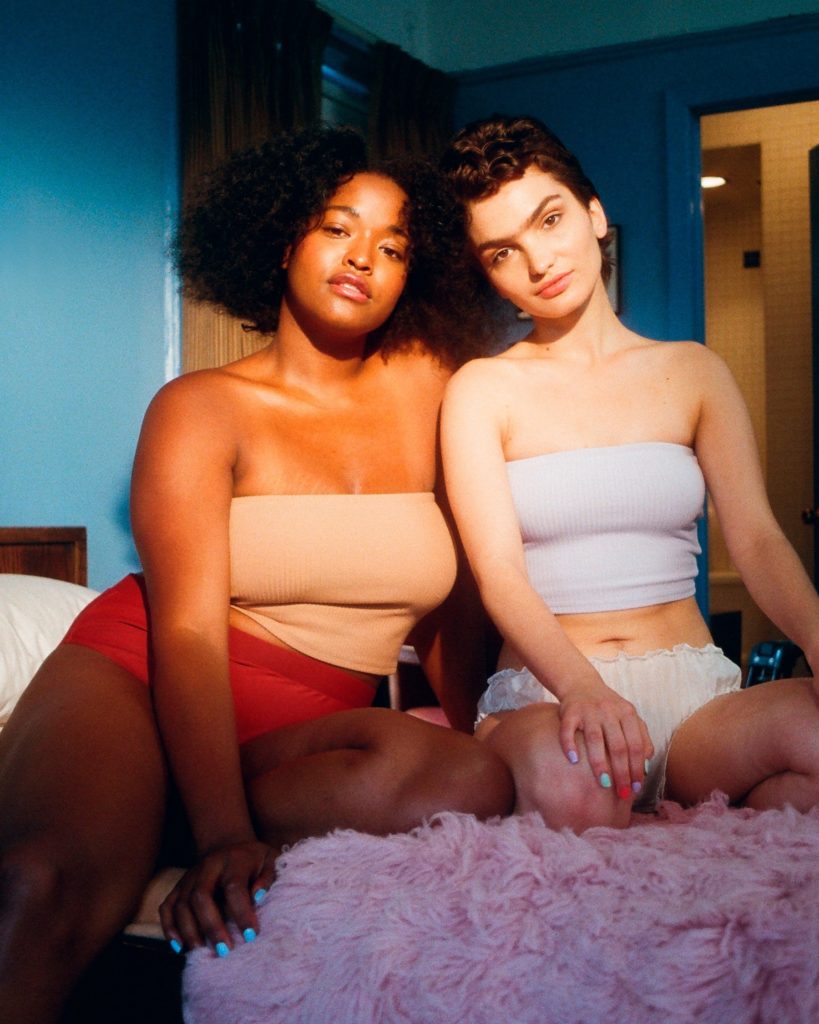 Two woman sitting on bed posing for the picture