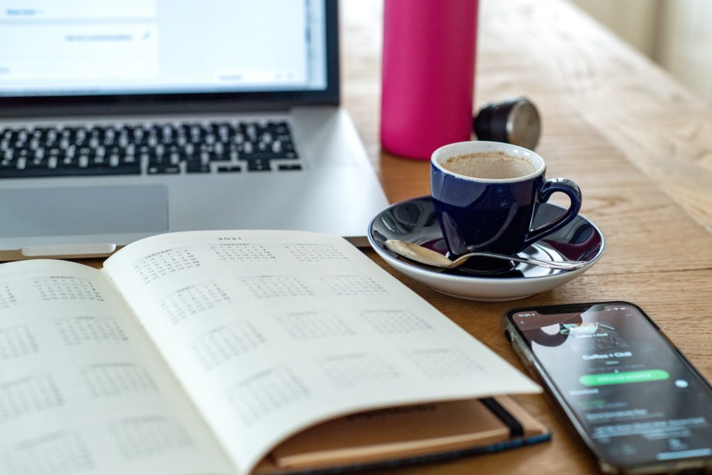 A laptop, coffee mug, mobile phone , a book on a table
