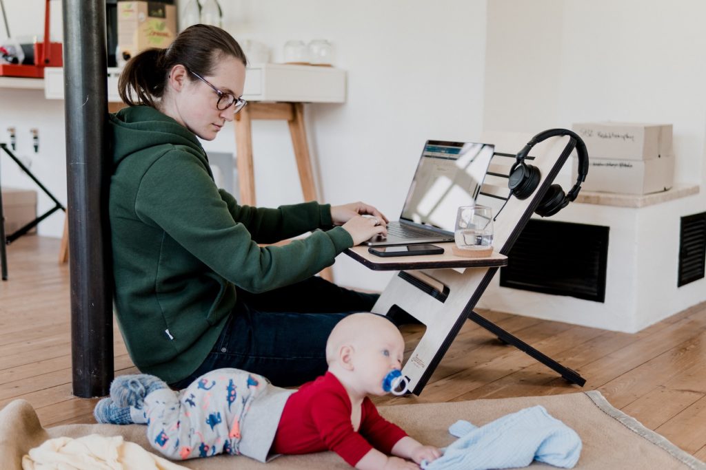 A woman working on her laptop at home with a baby 