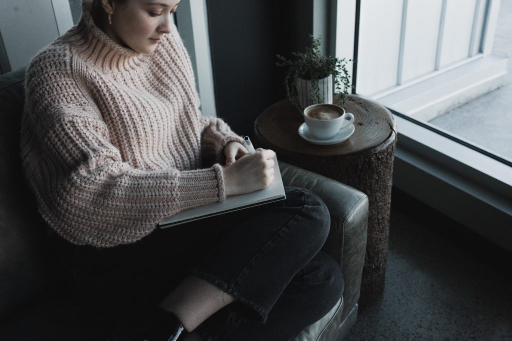 A woman writing while sitting on a couch