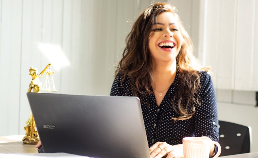 A woman laughing with laptop on the table