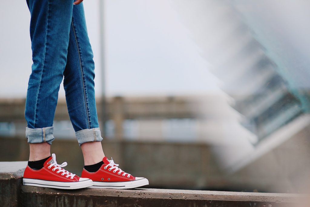 A pair of legs wearing denim and converse shoes