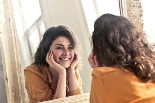 woman smiling looking at herself in the mirror
