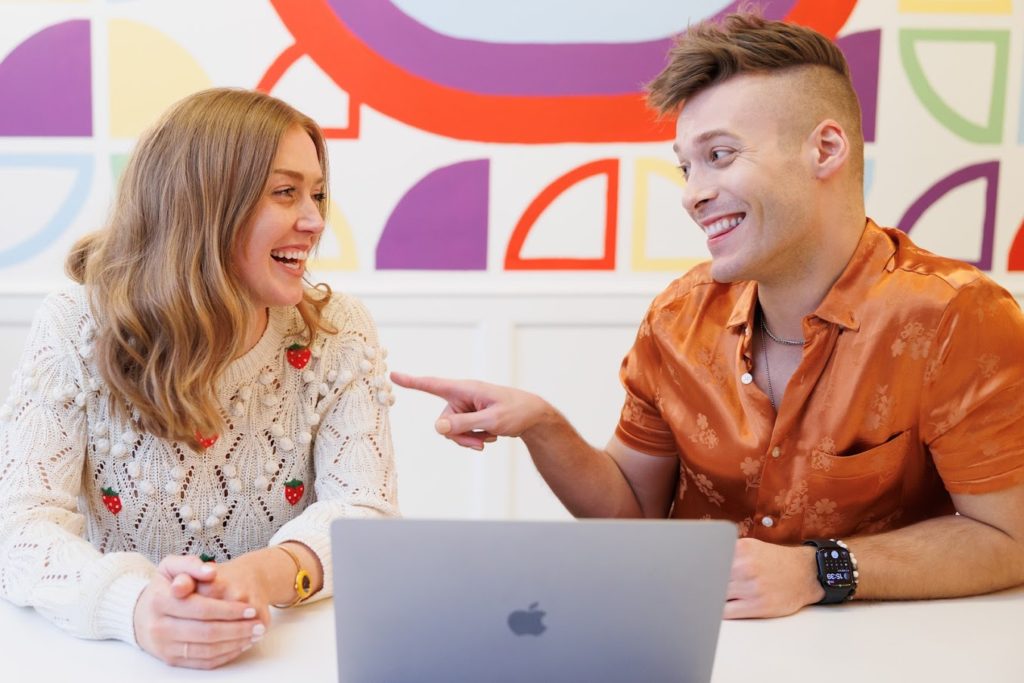 Man and woman talking and laughing in front of a computer