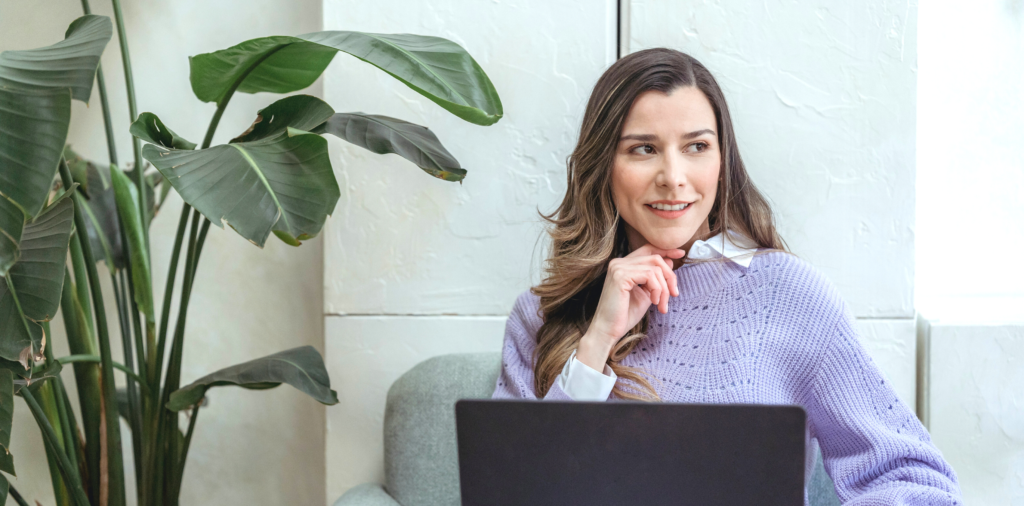 woman looking off into distance thinking with laptop on her lap