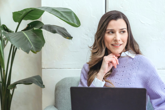 woman looking off into distance thinking with laptop on her lap