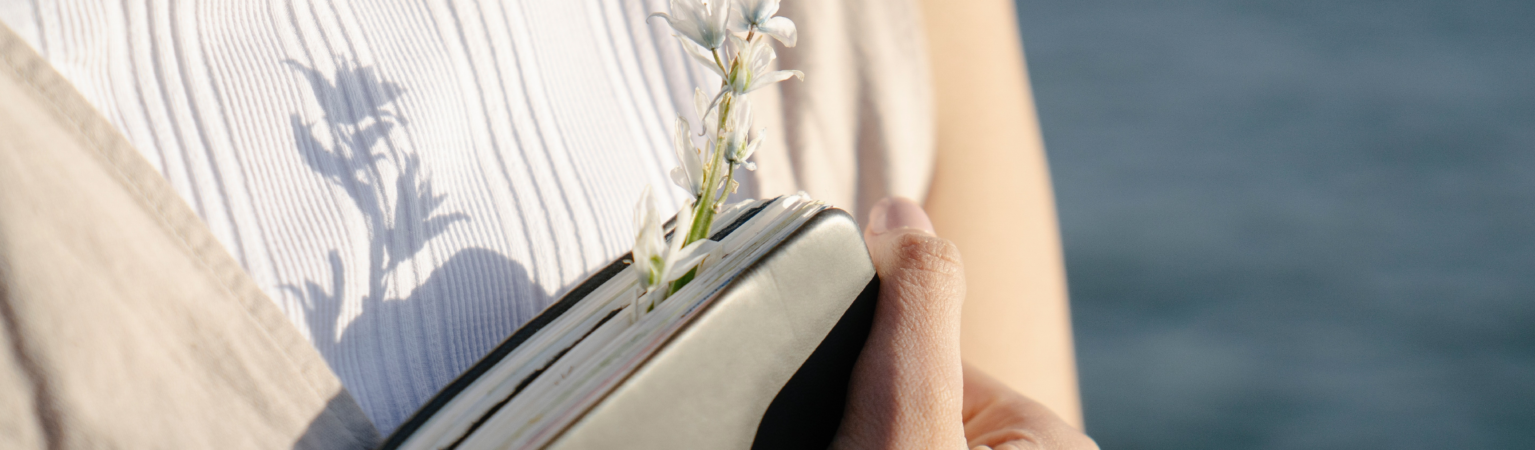 woman holding a journal with a flower in it