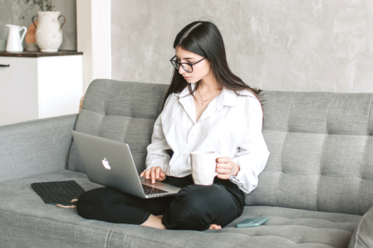 woman working on computer while sitting on couch