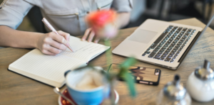 person taking notes while looking at computer