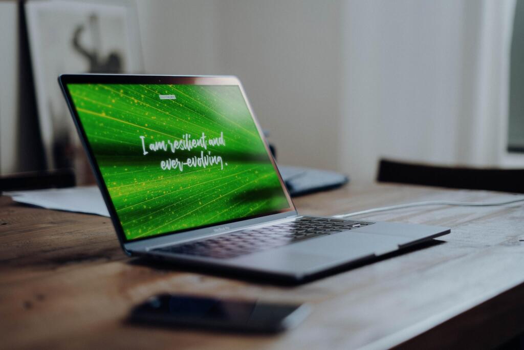 laptop with the quote "I am resilient and ever-evolving" written on it with a green leaf background