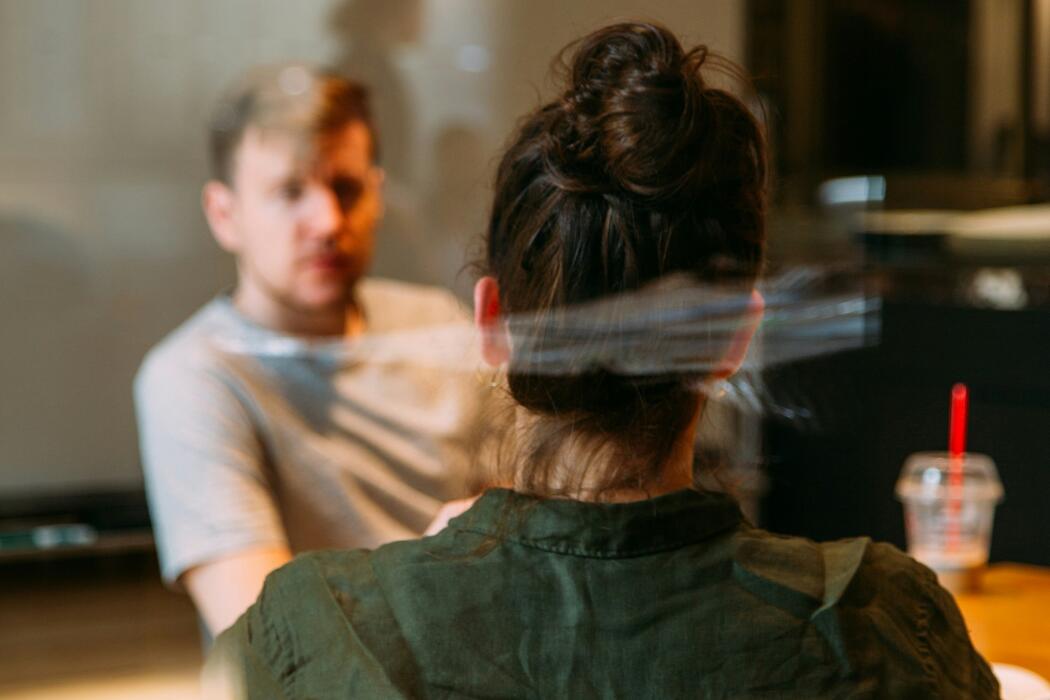 The back of a woman's head facing a man in a meeting room