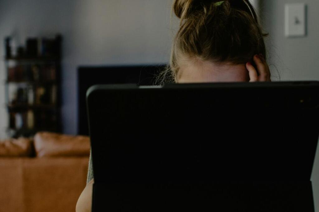 Woman behind tablet screen holding her head