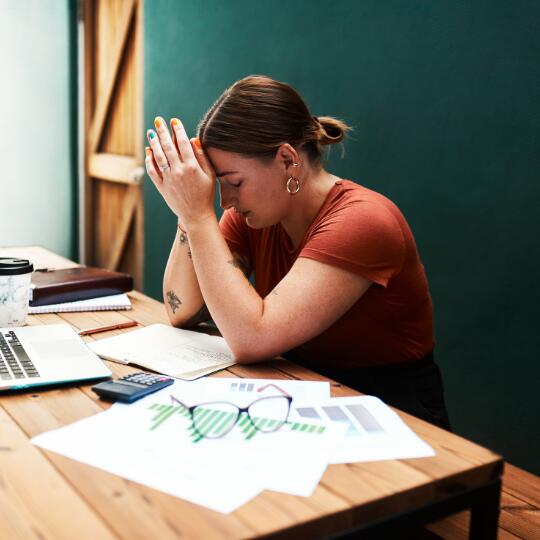 a young woman looking overwhelmed and frustrated at her desk