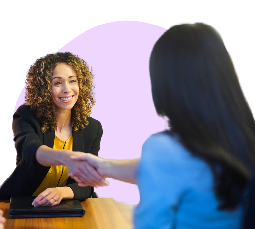 two women shaking hands across a table over an accepted job offer