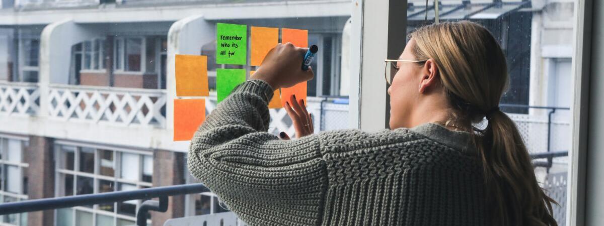 Woman writing on sticky notes on window