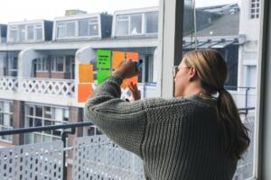 Woman writing on sticky notes on window