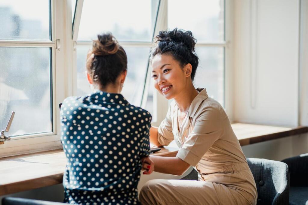 Woman talking to another woman near a window