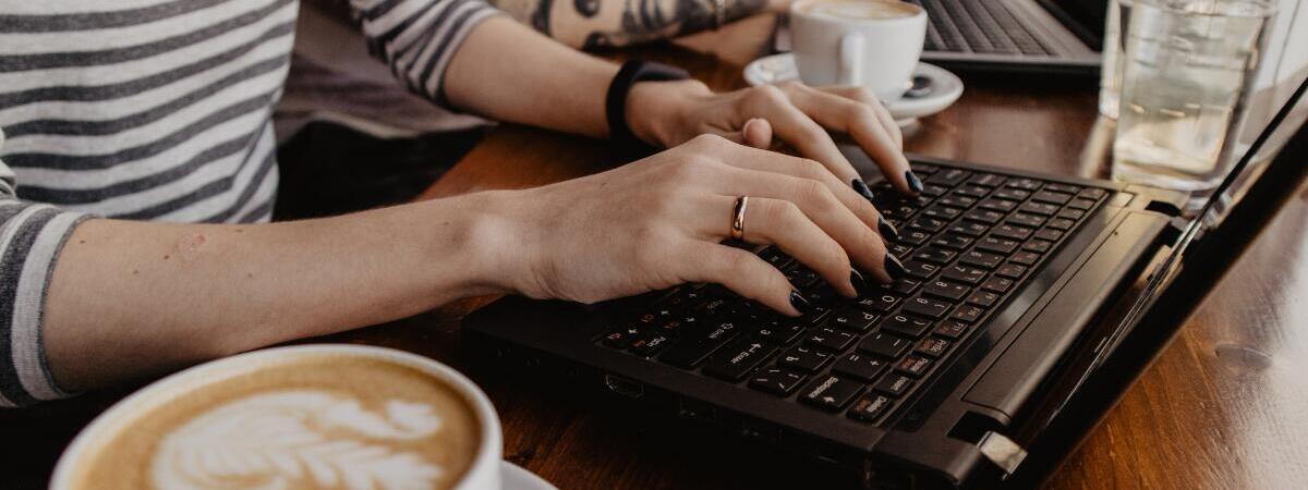 woman typing on laptop at a cafe