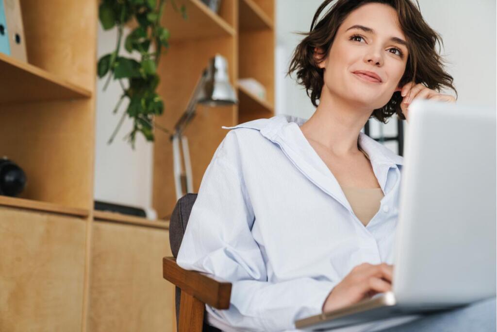 Women on laptop with pensive, smiling look