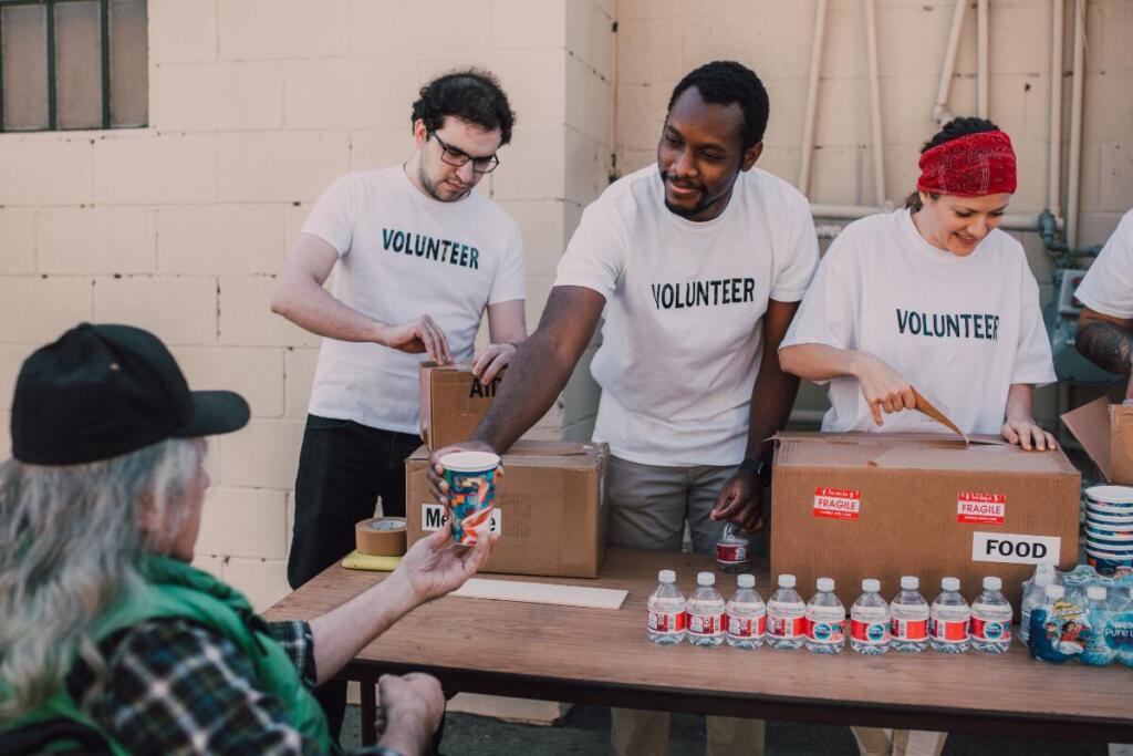 Volunteers handing hot drinks to people experience homelessness