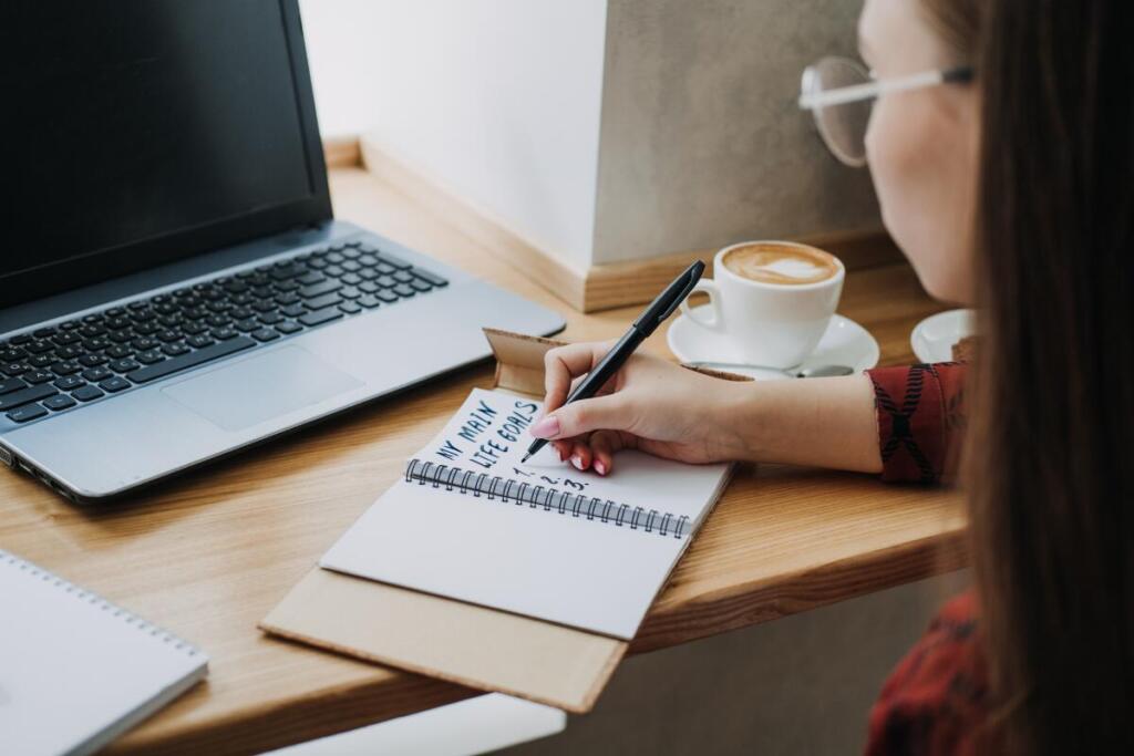 Woman writing down her goals on a notebook