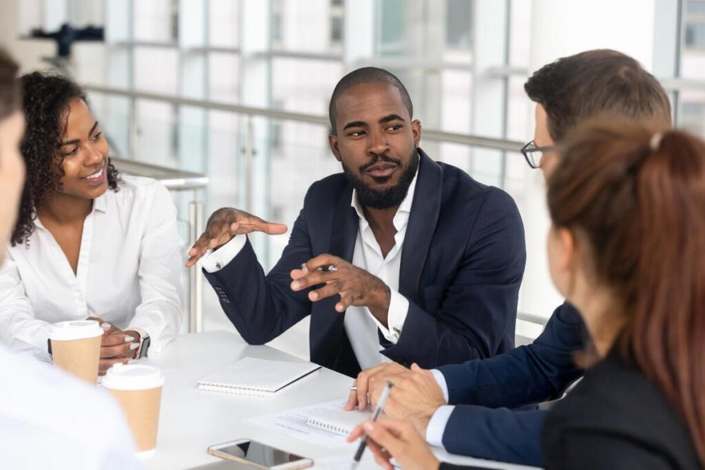 man in leading a discussion in a meeting at a table. Setting Long-Term Goals for Networking.