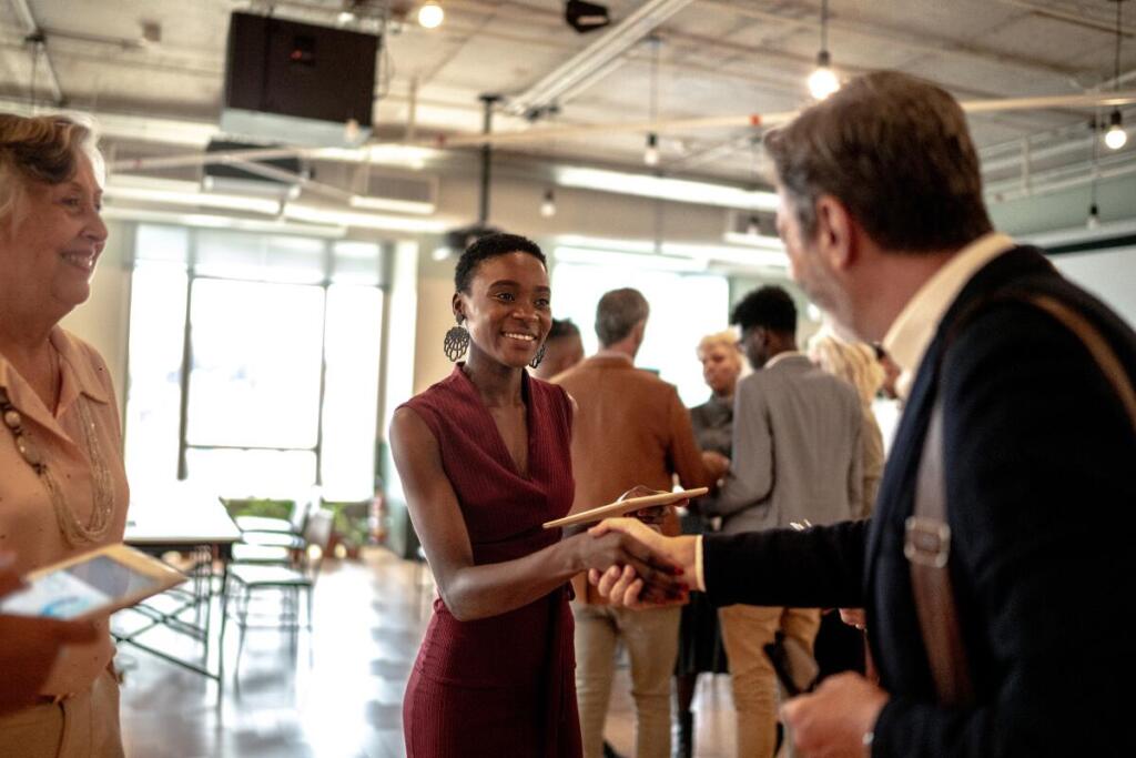 woman and man shaking hands at a cool networking event. setting better networking goals is about making meaningful connections.