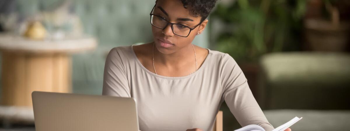 young women looking at computer while writing