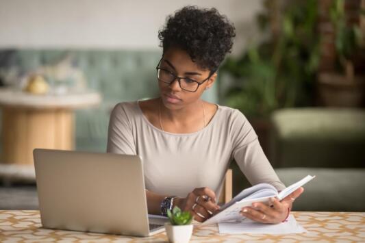 young women looking at computer while writing