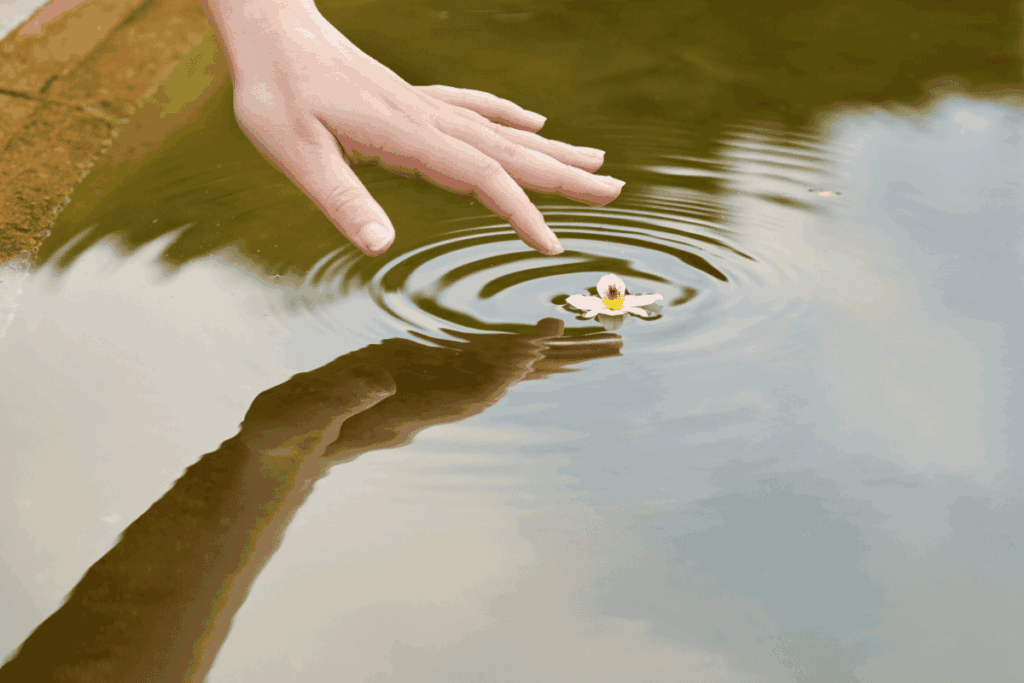 Hand touching water to create a ripple effect