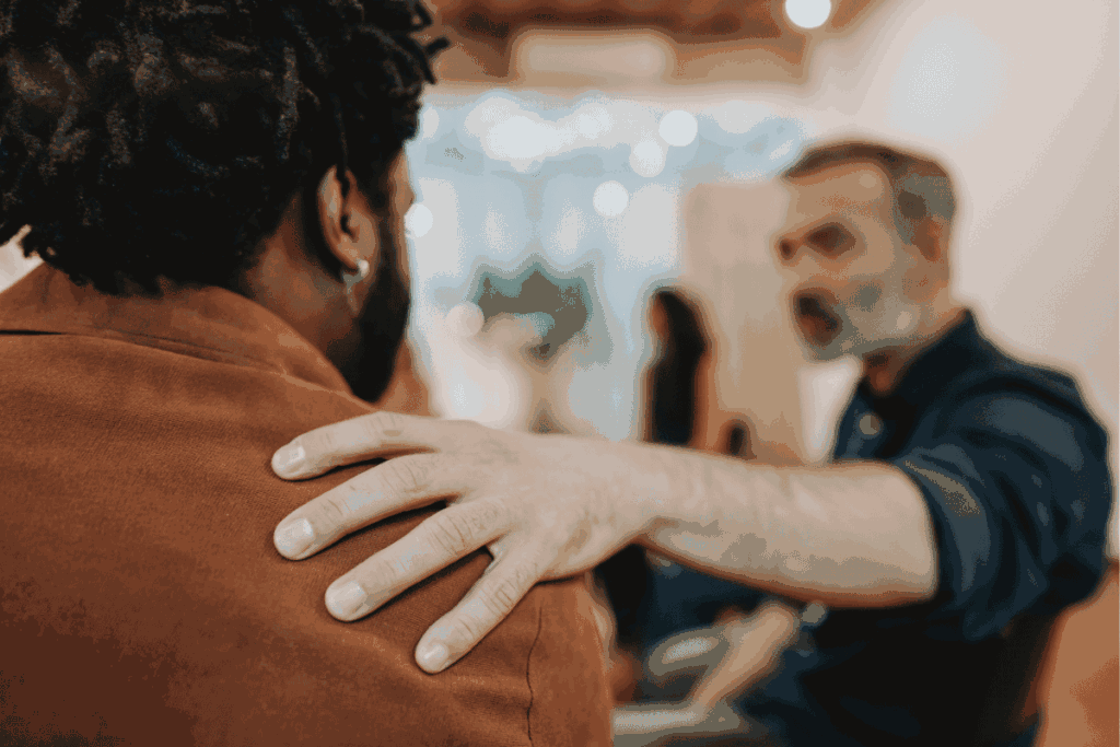 One man providing support to another with his hand on his shoulder.