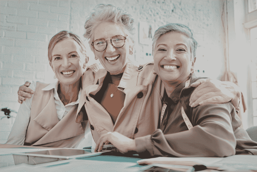 Three mature women smiling at the camera, excited about retirement.